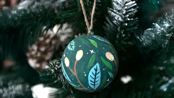 Dekorierte Kugel hängt am Weihnachtsbaum.