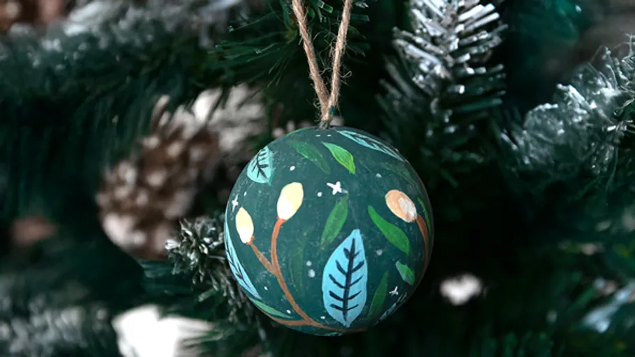Painted ornament hanging on Christmas tree.