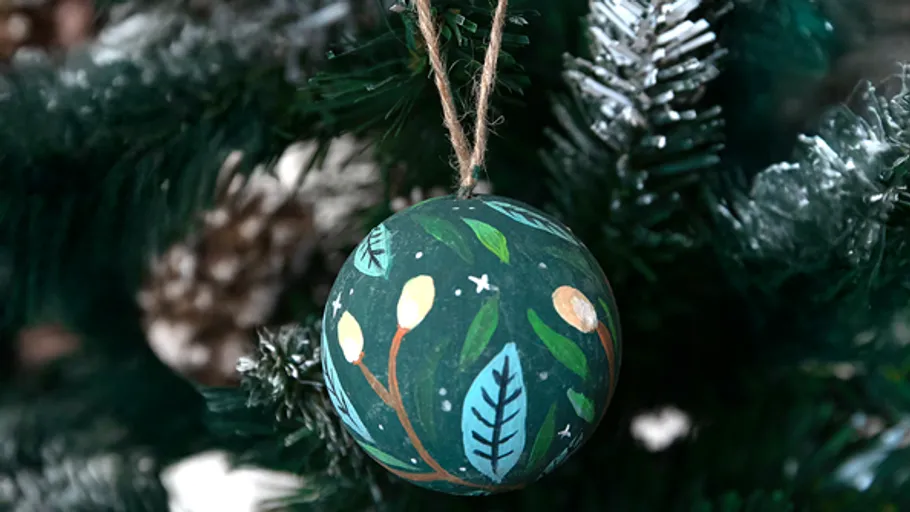 Hand-painted ornament hanging on Christmas tree.