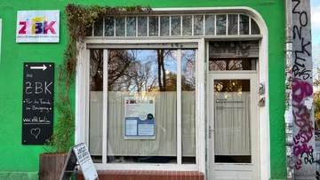 Grünes Schaufenster mit Glasfenstern und Schildern.