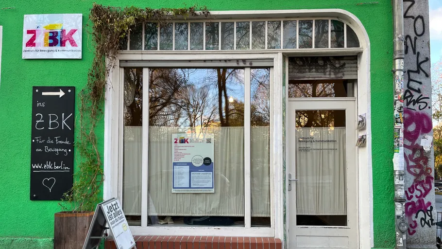 Green storefront with glass windows and signs.