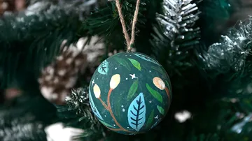 Bemaltes Ornament hängt am Weihnachtsbaum.