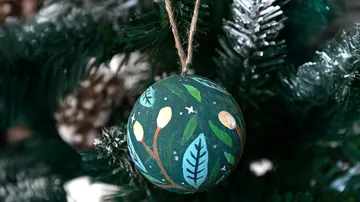 Bemalter Schmuck hängt am Weihnachtsbaum.