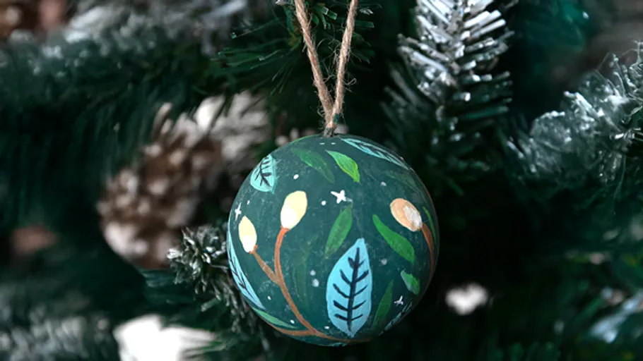 Painted ornament hanging on Christmas tree.