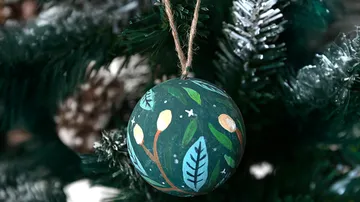 Painted ornament hanging on Christmas tree.
