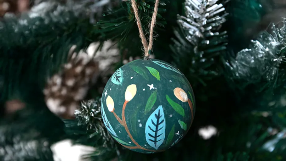 Painted ornament hanging on Christmas tree.