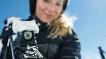 Person adjusting ski bindings on snowy mountain.