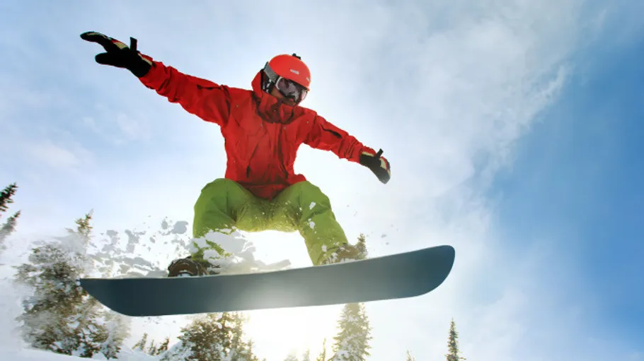 Snowboarder springt hoch gegen klaren Himmel.