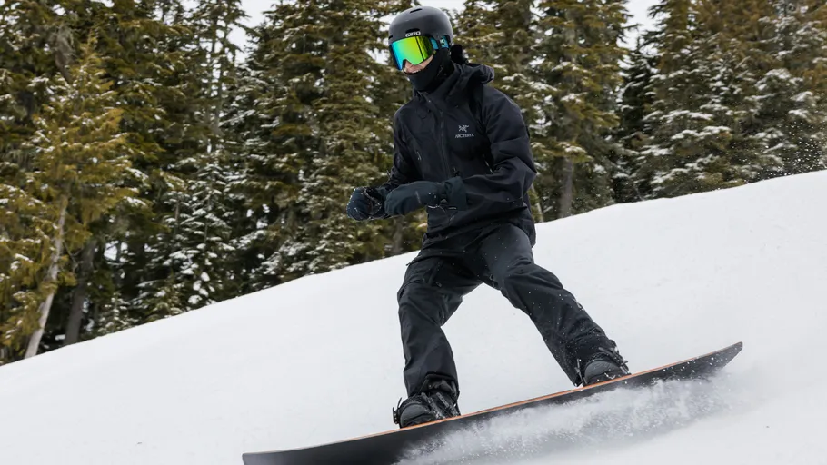 Person snowboardet bergab, umgeben von Bäumen.