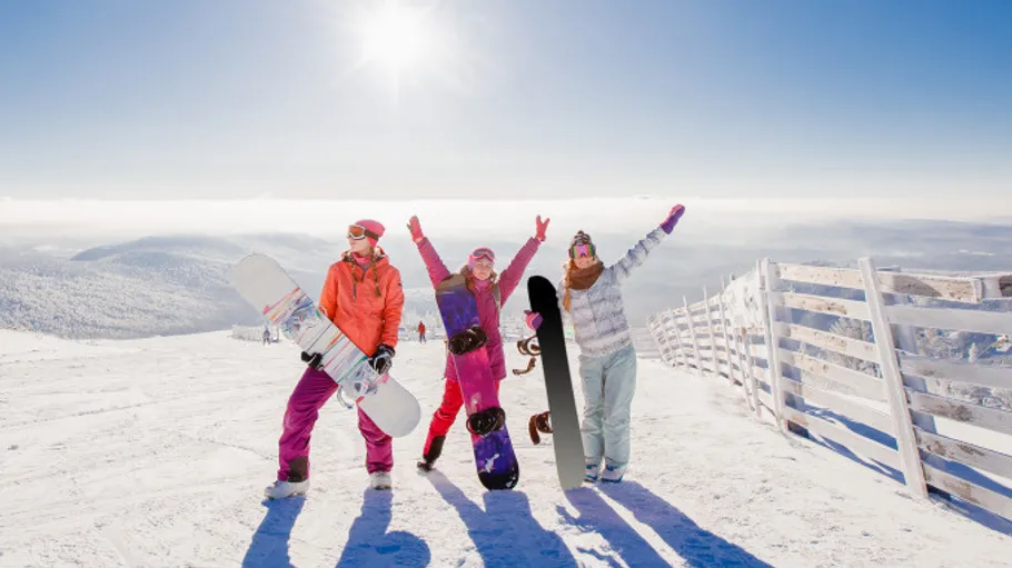 Drei Snowboarder feiern auf verschneitem Berg.