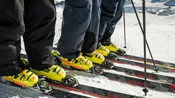 Skiers with bright boots on snowy slope.