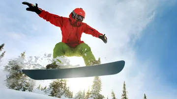 Snowboarder springt in schneebedeckter Berglandschaft.