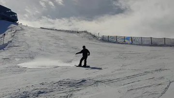 Snowboarder gliding down a snowy slope.
