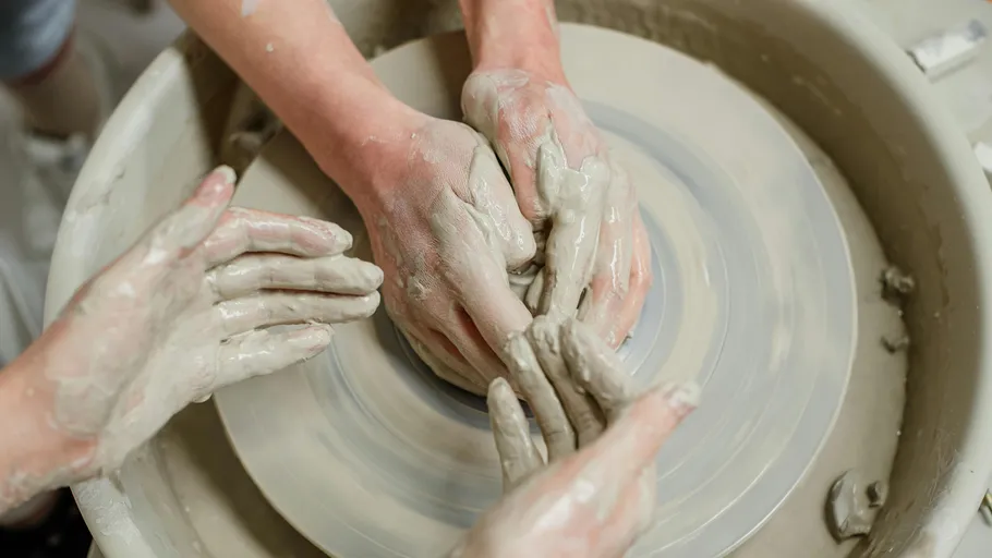 Hands molding clay on a pottery wheel.