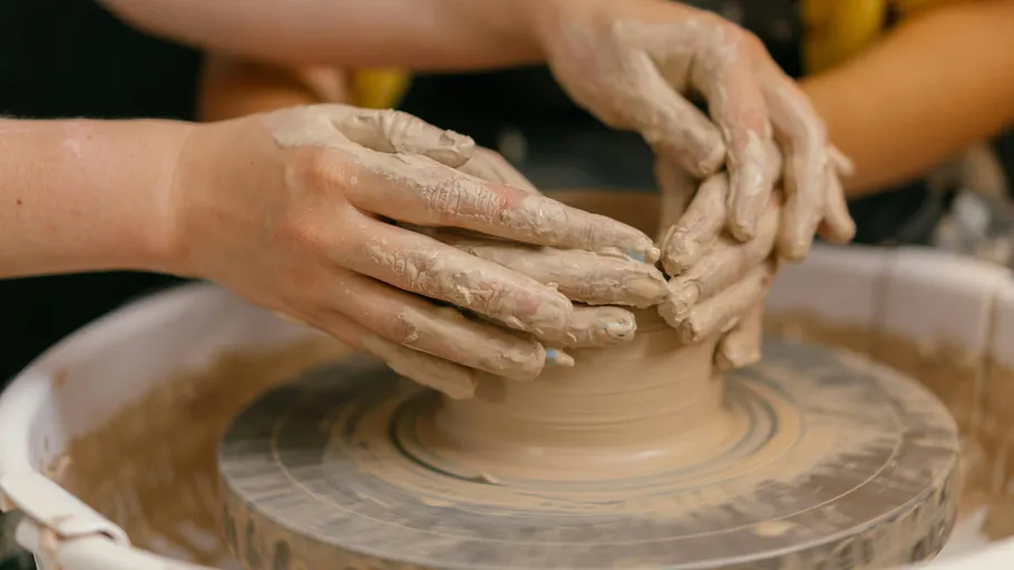 Hands shaping clay on a pottery wheel.