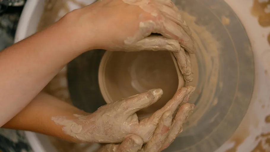 Hands shaping clay on a pottery wheel.