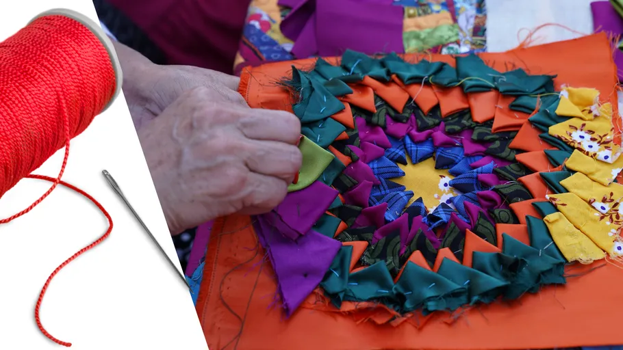 Hands sewing colorful fabric pattern.