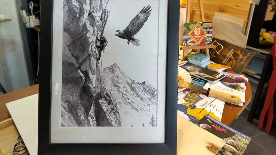 Framed drawing of climber and bird on mountain.