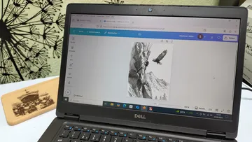 Laptop displaying eagle artwork next to wall decor.