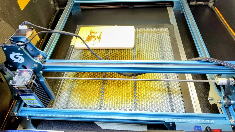 Laser engraver etching design on wooden board.