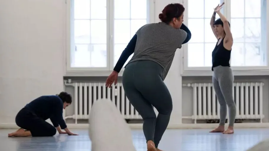 Three people practicing dance in a studio.