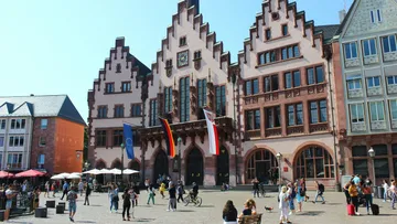 Historic building with flags on a sunny square.