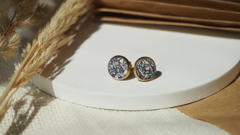 Colorful earrings on white round platform.