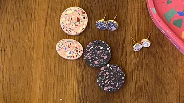 Terrazzo earrings on wooden table, colorful and patterned.