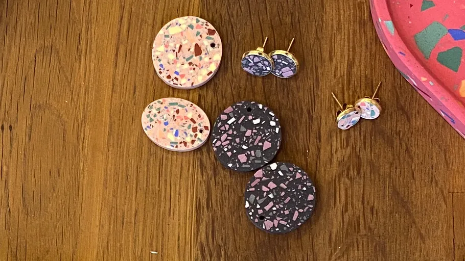 Terrazzo-Ohrringe auf Holztisch, bunt und gemustert.