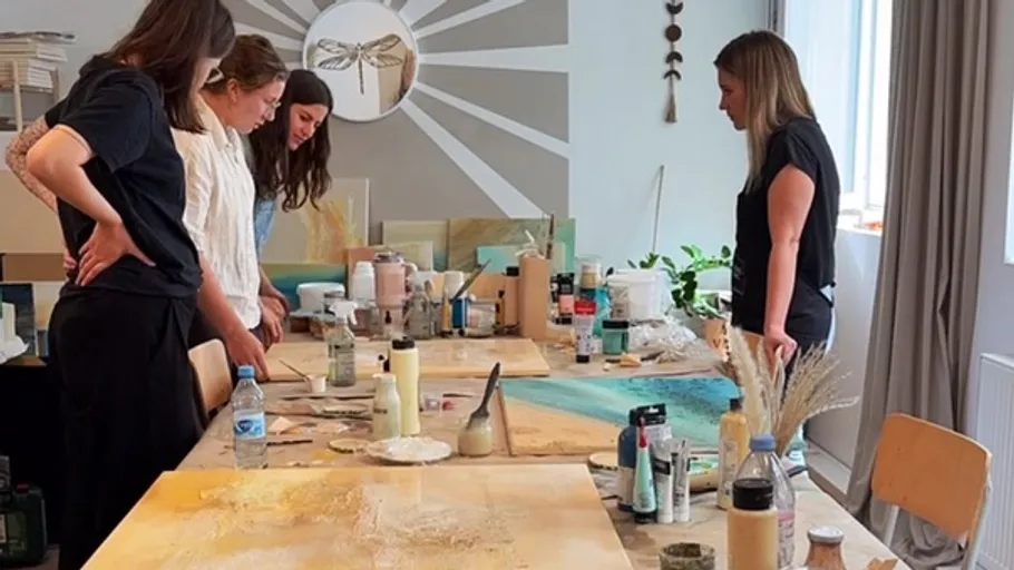 People painting at a table in a studio.