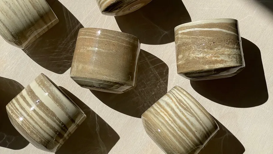 Patterned cups casting shadows on a surface.