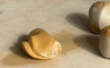 Clay pieces rolled on wooden surface.