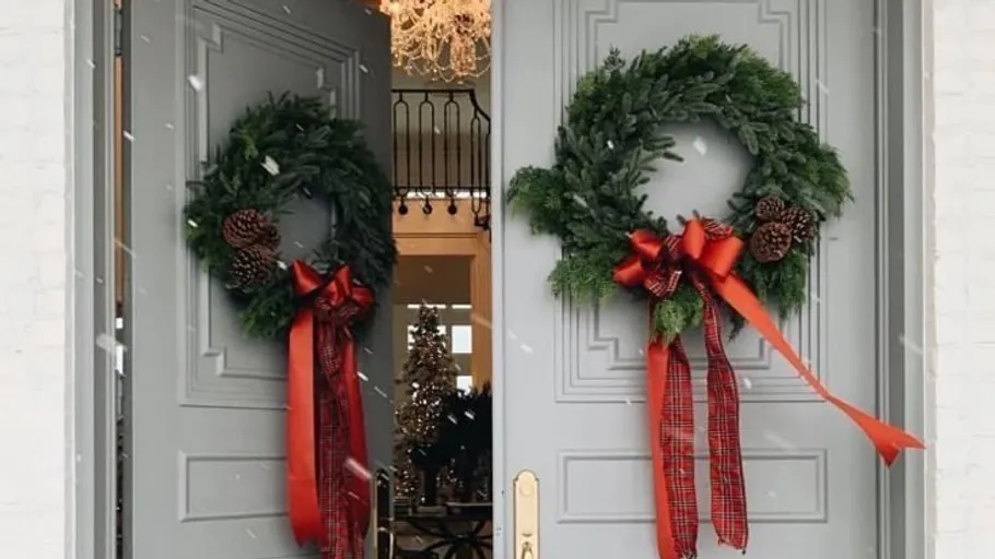 Two wreaths with red bows on gray doors.