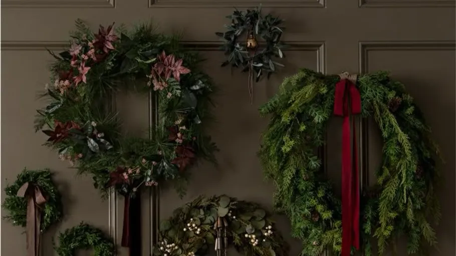 Various Christmas wreaths hanging on wall.