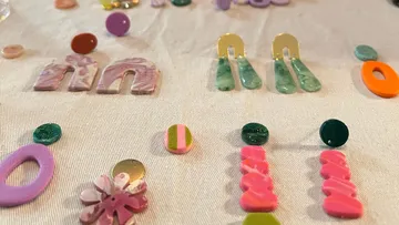 Bunte Ohrringe auf weißem Stoff ausgestellt.