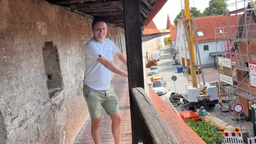 Man smiling on historic town wall path.