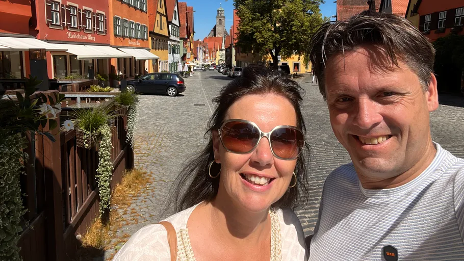 Two people smiling on a cobblestone street.