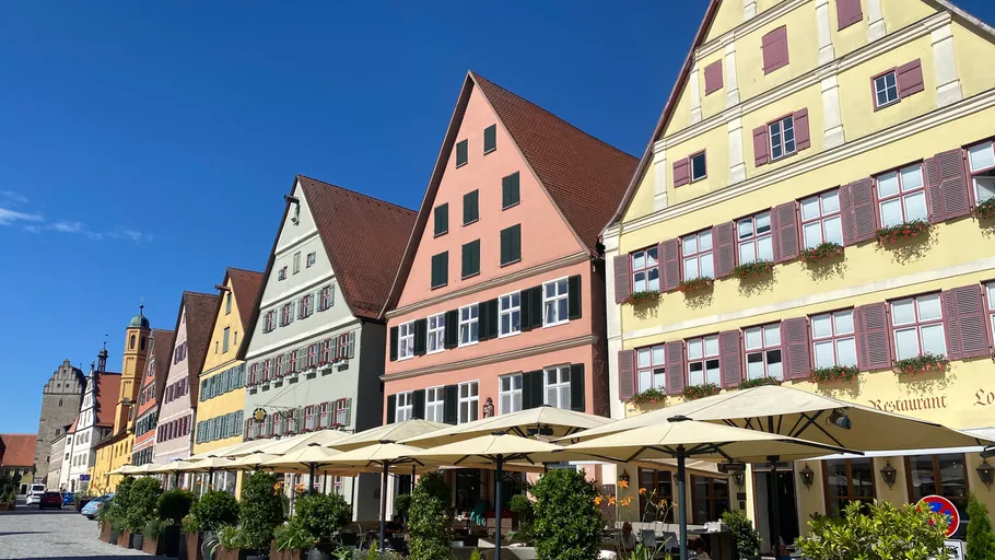 Bunte Gebäude mit Straßencafé und blauem Himmel.