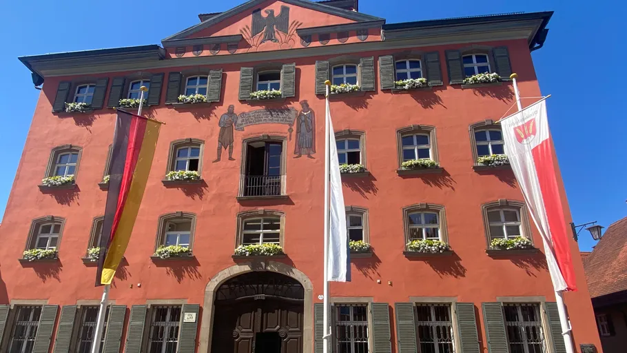 Rotes Gebäude mit Fahnen und Wandkunst.