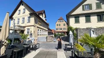 Person spaziert in sonnigem deutschen Dorf.