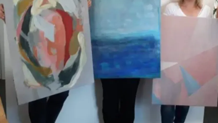 People holding abstract paintings indoors.