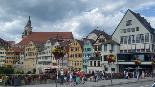 Personen spazieren an bunten historischen Gebäuden vorbei.