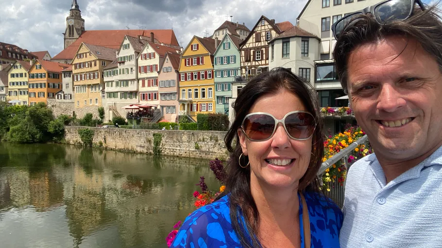 Couple smiling in front of colorful townhouses.