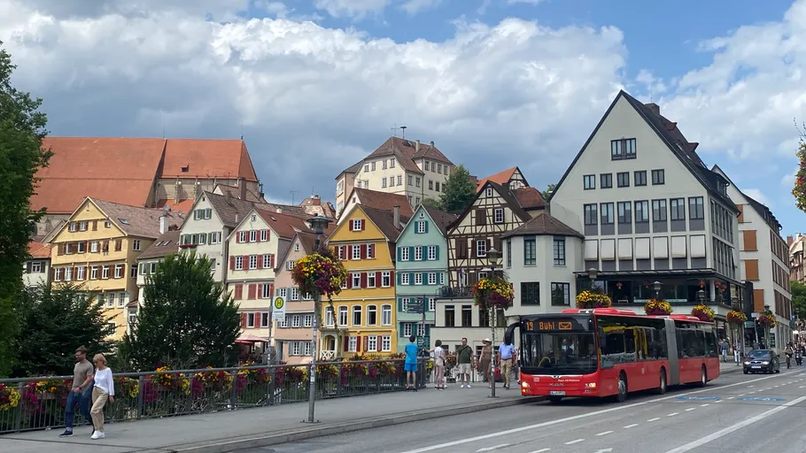 Roter Bus passiert bunte historische Gebäude.