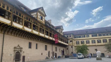 Historisches Gebäude mit Hof unter bewölktem Himmel.