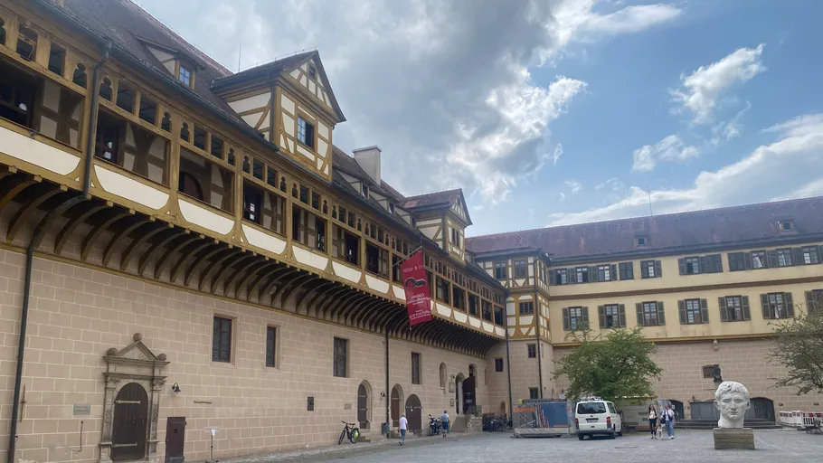 Historic building with courtyard under cloudy sky.