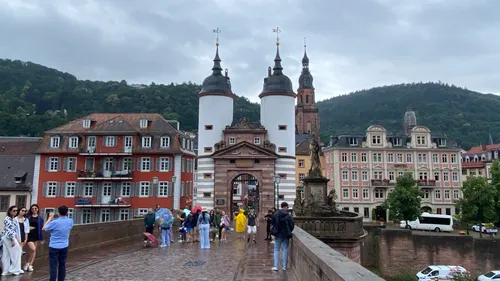 People walking on historic bridge with towers.