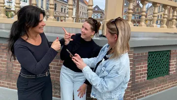 Three women talking, smiling on a city street.
