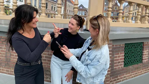 Drei Frauen reden, lächeln auf einer Stadtstraße.