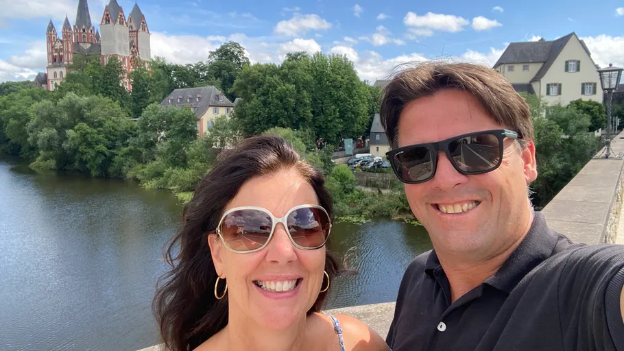 Couple smiling on bridge with cathedral view.